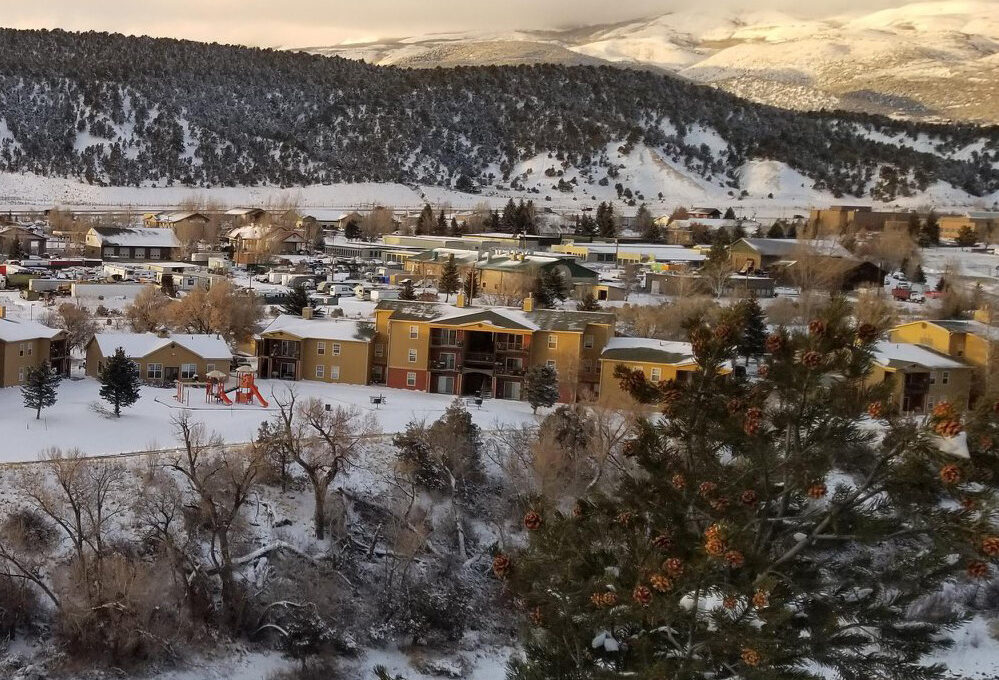 Snow-covered town with buildings and mountains in background.